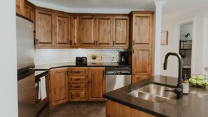 Una cocina con armarios de madera, un lavamanos de acero inoxidable y una encimera negra.