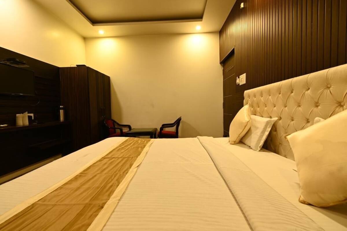 A hotel room with a large bed, a television, a desk, and a chair.