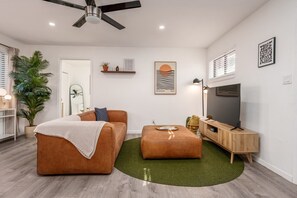Un salon moderne avec un canapé, un pouf et un meuble pour la télévision.