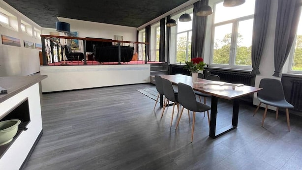 A modern kitchen with a dining area, large windows, and a view of greenery outside. - Ecolodge Loft, 180qm Raumwunder für bis zu 8 Personen, 5km zu Nordsee / Büsum (Oesterdeichstrich)