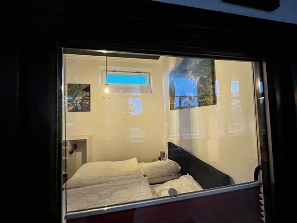A room with a bed, a nightstand, a lamp, and a window with a view of a building and trees. - Ecolodge Loft, 180qm Raumwunder für bis zu 8 Personen, 5km zu Nordsee / Büsum (Oesterdeichstrich)