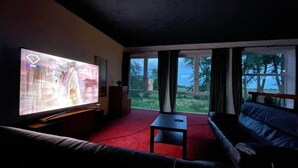 A living room with a large TV, a sofa, a small table, and a view of the outdoors through large windows. - Ecolodge Loft, 180qm Raumwunder für bis zu 8 Personen, 5km zu Nordsee / Büsum (Oesterdeichstrich)
