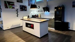 A modern kitchen with a central island, pendant lighting, and artwork on the walls. - Ecolodge Loft, 180qm Raumwunder für bis zu 8 Personen, 5km zu Nordsee / Büsum (Oesterdeichstrich)