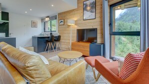 A modern interior with a wooden ceiling, a sofa, a dining table, and a TV. - Alptitude Beauvallon Petit - stylish and spacious property for 6 people (Morzine)