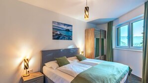 A bedroom with a bed, bedside tables, a wardrobe, a painting, and a window with curtains.