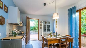 Una cocina moderna con armarios de madera, un comedor con mesa y sillas de madera, y vistas a un jardín a través de un amplio ventanal.