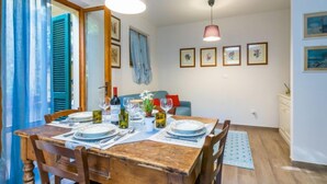 Un comedor con una mesa de madera dispuesta para cuatro, un sofá azul al fondo y un mueble pequeño a la derecha.