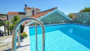 A swimming pool with a stone wall and metal ladder. - Vacation home Aurora by Interhome (Skradin)