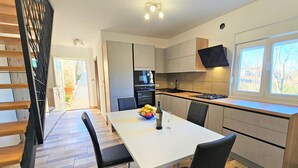A modern kitchen with a dining area, wooden flooring, and a large window. - Vacation home Aurora by Interhome (Skradin)