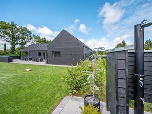 Ett modernt hus med en välskött gräsmatta, en uteplats och en liten trädgård.