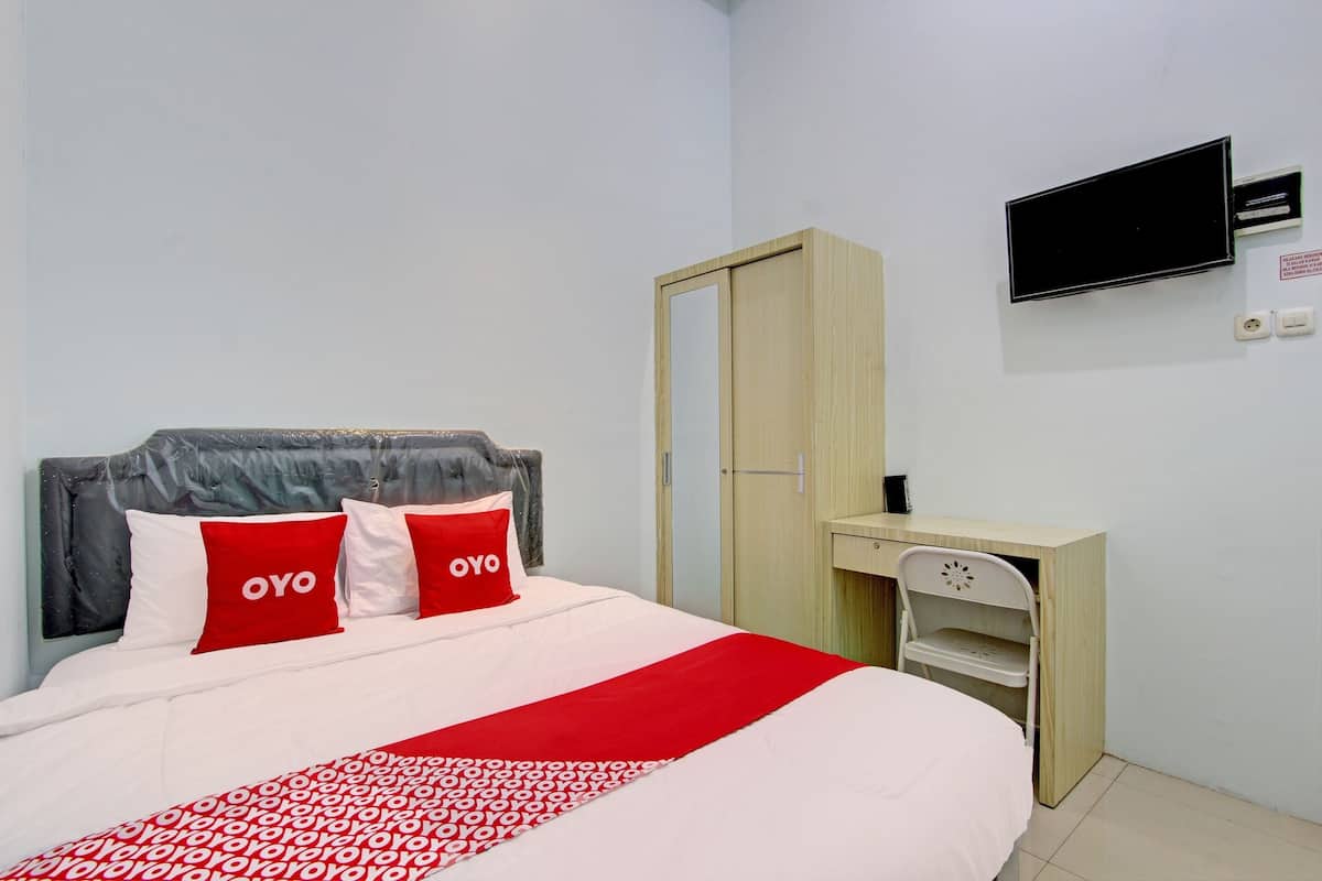 A bedroom with a bed, a wardrobe, a desk, and a television.