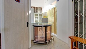 Un corridoio con una porta in legno con la scritta '104', un tavolo in vetro con cornice nera e una panca di legno.