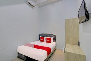 A bedroom with a bed, a wooden nightstand, a wall-mounted TV, and a ceiling-mounted air conditioner. - Hotel O New Puspa Residence (Semarang)