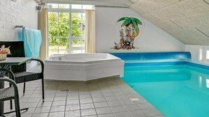 A swimming pool with a mural, a seating area, and a window with curtains.