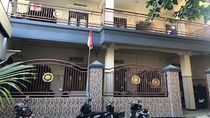 Un edificio residencial de varios pisos con entrada protegida, balcones y motocicletas estacionadas.