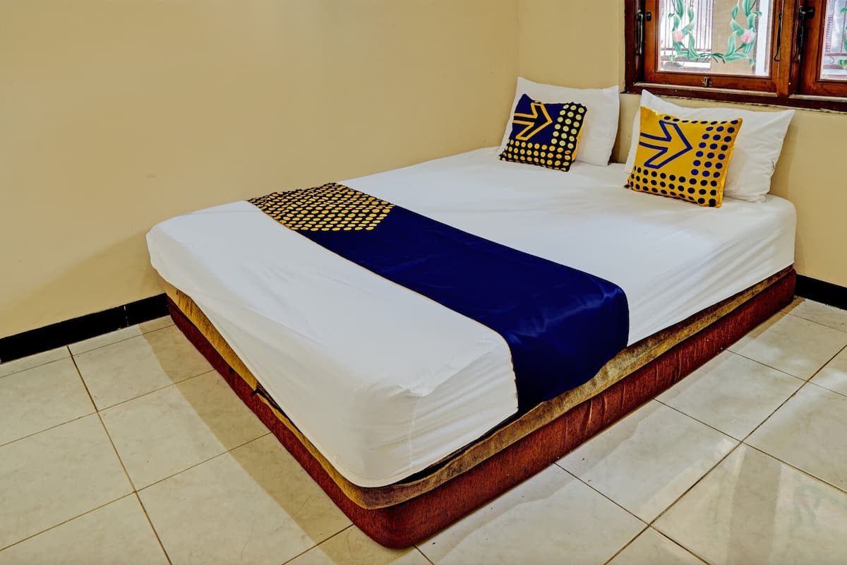 A bed with white and blue bedding, two pillows with yellow and black patterns, and a wooden headboard.