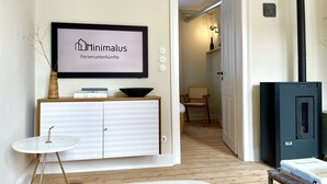 Un salon minimaliste avec un panneau décoratif encadré, une petite table, un canapé et un meuble noir.