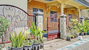 A building with a gated entrance, potted plants, and a tiled pathway. - OYO 93108 Homestay H Syarif Syariah – RA Kartini (Gresik)