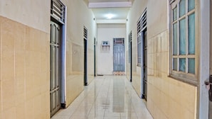 A corridor with tiled walls and floor, doors, and windows. - OYO 93108 Homestay H Syarif Syariah – RA Kartini (Gresik)