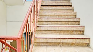 A staircase with a red metal railing and beige steps. - OYO 93108 Homestay H Syarif Syariah – RA Kartini (Gresik)