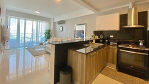 Una cocina moderna con una isla central, electrodomésticos de acero inoxidable y un amplio ventanal que proporciona luz natural.