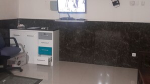 Un espace d’accueil doté d’un téléviseur à écran plat fixé au mur, d’un bureau avec un ordinateur et d’un coin salon comprenant un banc et une chaise.