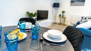 Ein Essbereich mit einem Tisch für zwei Personen, gedeckt mit Tellern, Gläsern und Besteck.