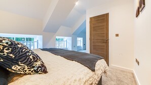 Ein Schlafzimmer mit einem großen Bett, einer Holztür und Blick auf einen Balkon.