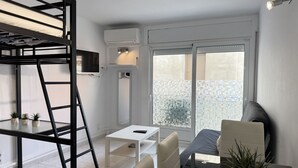 A compact room with a bunk bed, a small table, a sofa, and a potted plant. - Agi Estrella de Mar 2 Apartamento for rent in Roses Girona. (Roses)