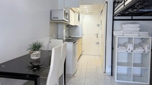 A compact kitchen with a dining area, a microwave, and a shelf with folded towels. - Agi Estrella de Mar 2 Apartamento for rent in Roses Girona. (Roses)