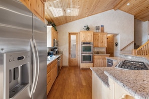 A modern kitchen with stainless steel appliances, wooden cabinets, and a granite countertop.