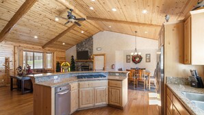 A spacious kitchen with wooden cabinets, granite countertops, and a central island. - Hot Tub, Game Room, Large Deck w/ Mountain Views, 4BDR | Paw Print by AvantStay (Big Bear Lake)