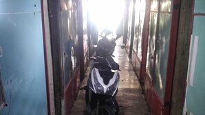 A narrow corridor with a motorcycle parked at the end. The corridor has blue walls with red trim and a concrete floor. - Hotel O Barak Tambunan NearBelawan Port (Medan)