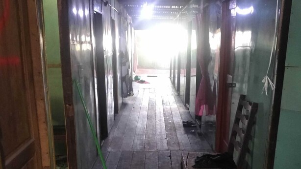 A narrow corridor with wooden flooring, benches, and a broom leaning against the wall. - Hotel O Barak Tambunan NearBelawan Port (Medan)