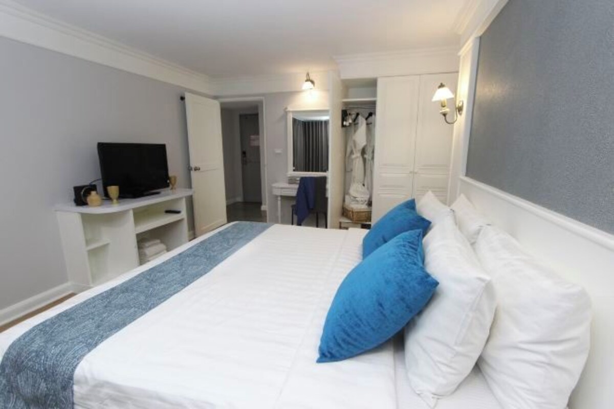 Une chambre à coucher avec un lit, une télévision, une armoire et un miroir.