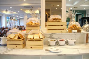 A buffet setup with bread baskets and small bowls of condiments on a marble counter. - Coco Beach Hotel Jomtien Pattaya (Pattaya)