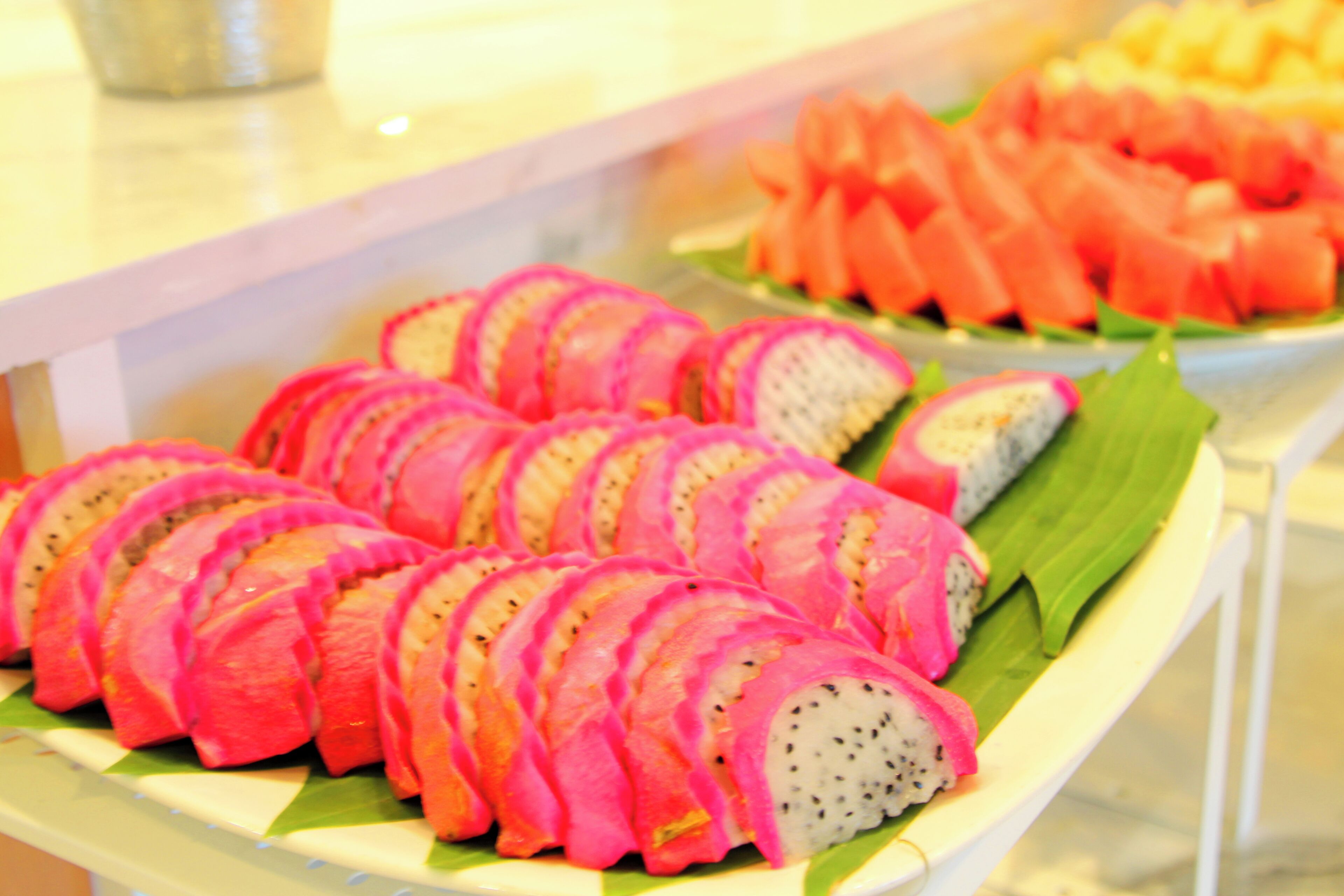 A buffet with various food items including pink dragon fruit slices and watermelon.