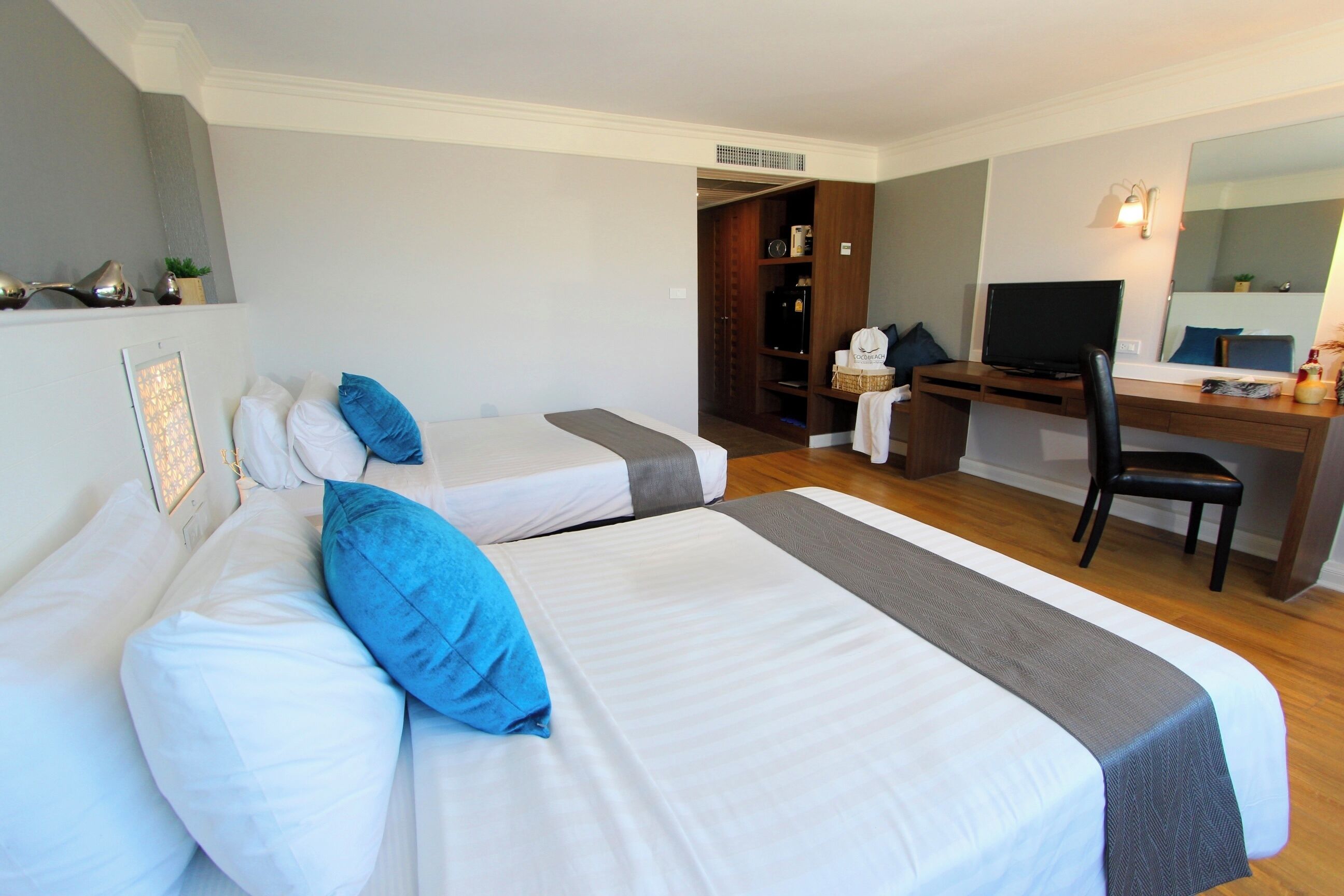 A hotel room with two beds, a desk, a chair, a television, and a wardrobe.