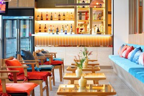 A bar area with shelves of bottles, seating with cushions, and a refrigerator. - Coco Beach Hotel Jomtien Pattaya (Pattaya)