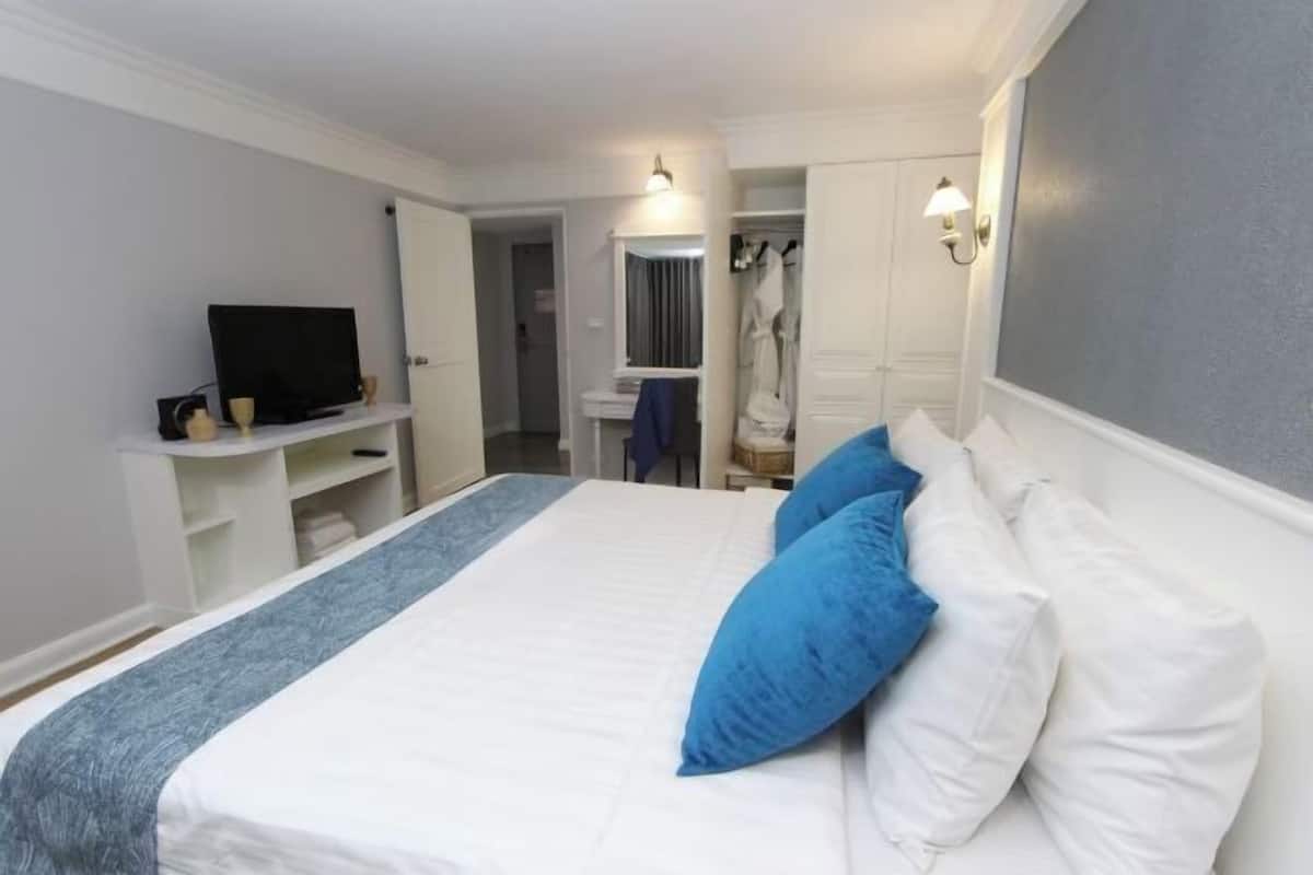 Un dormitorio con cama, televisor, armario y espejo.
