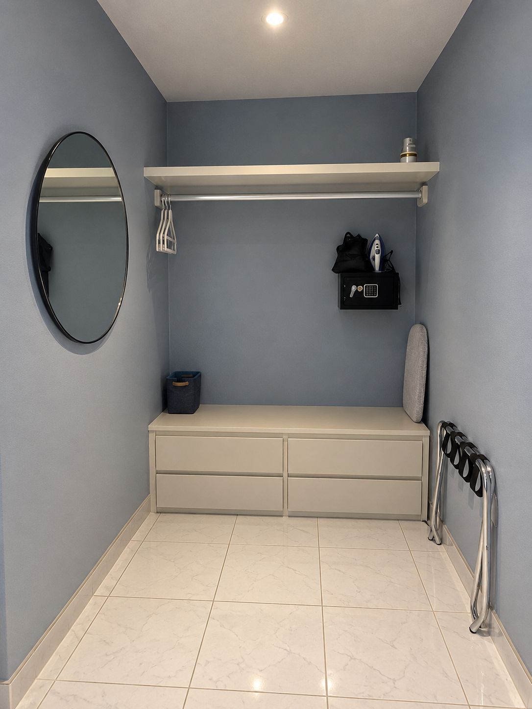 Un baño con espejo, toallero, repisa con artículos de aseo y radiador.