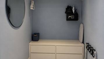 Un baño con espejo, toallero, repisa con artículos de aseo y radiador.