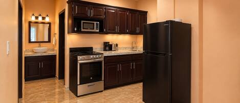A kitchen with dark wood cabinets, a stainless steel oven, a black refrigerator, and a microwave.
