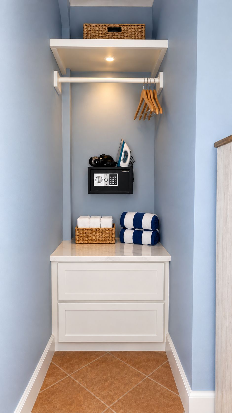 Un coin de pièce avec un meuble de rangement blanc, un panier en osier et un appareil noir fixé au mur.