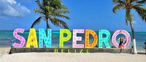 A beach sign with 'SAN PEDRO BELIZE' written in colorful letters.