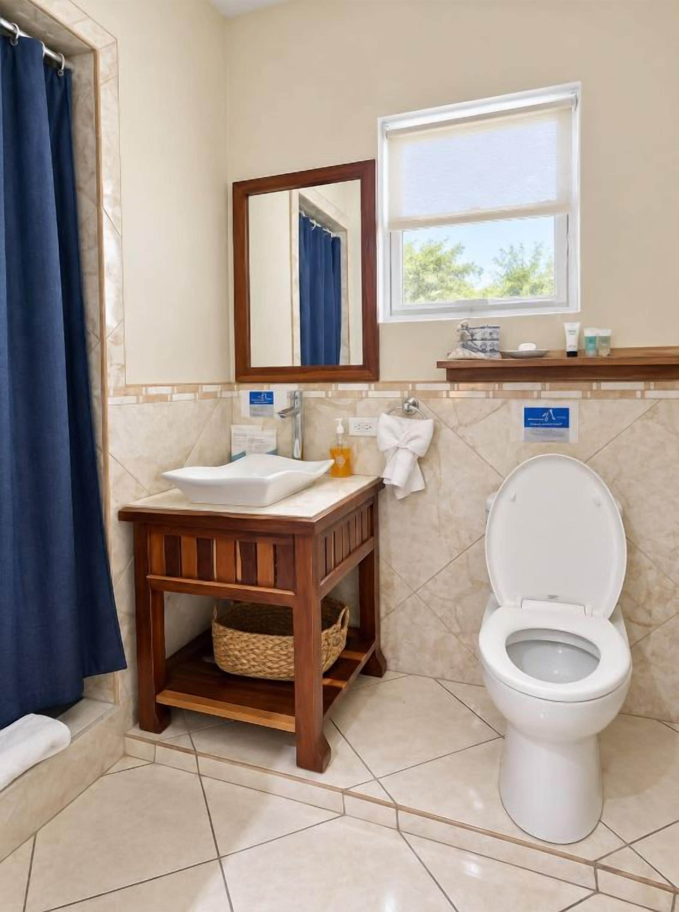 Un baño con inodoro, lavamanos, espejo y ventana.