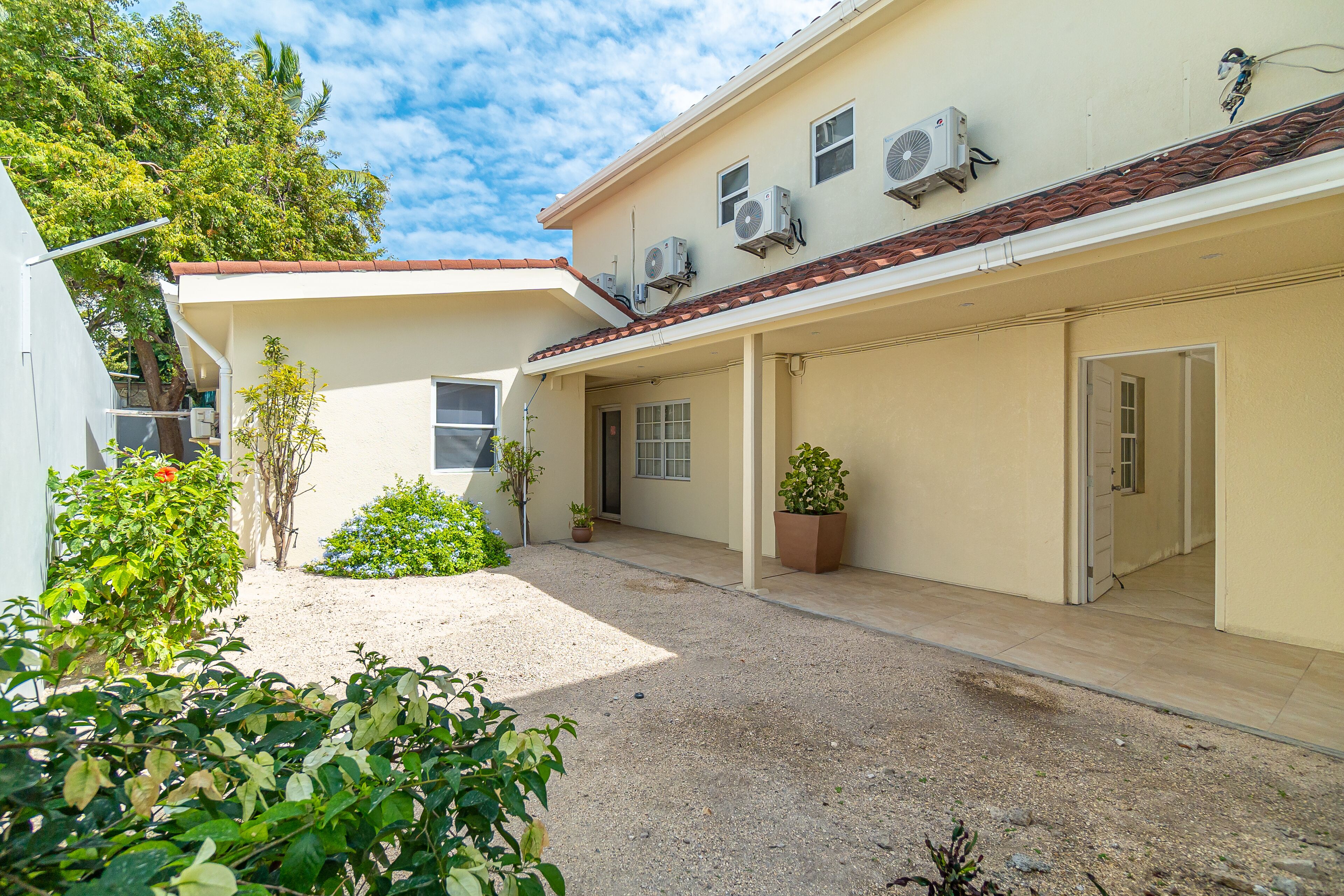 A building with a covered patio area, air conditioning units, and potted plants.