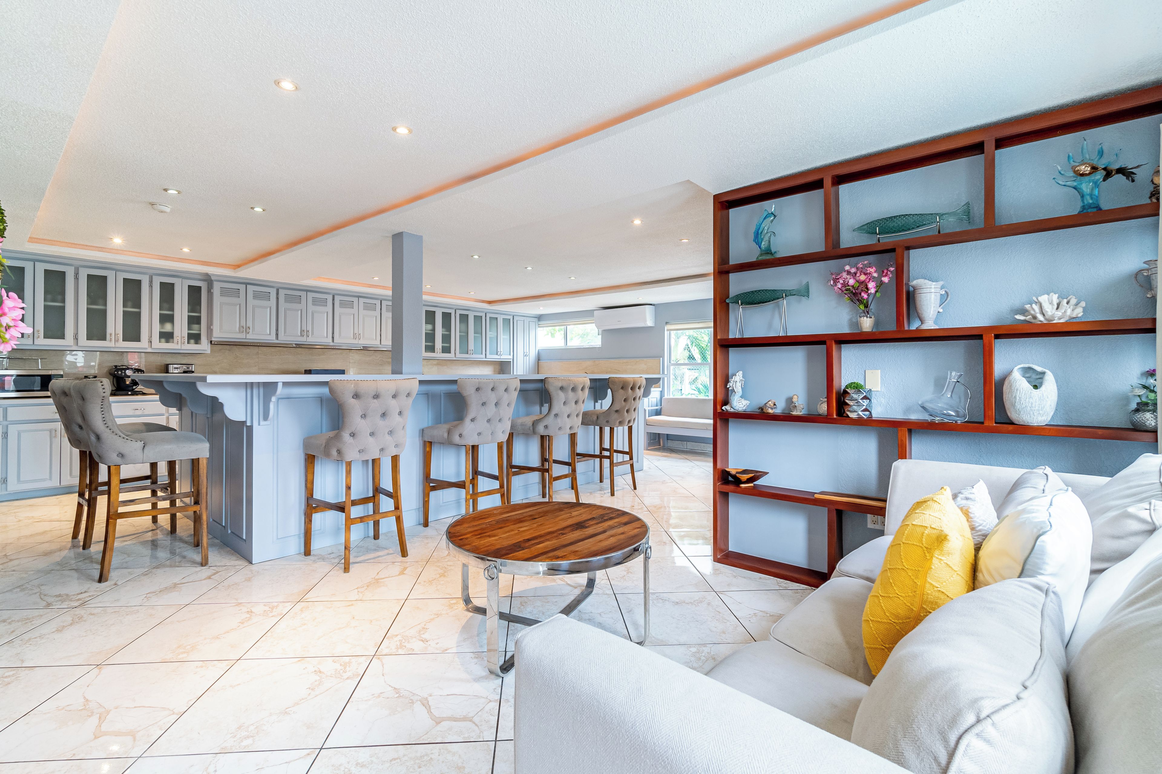 Una cucina moderna con sgabelli da bar, un tavolo da pranzo e un'area living con divano ed elementi decorativi.