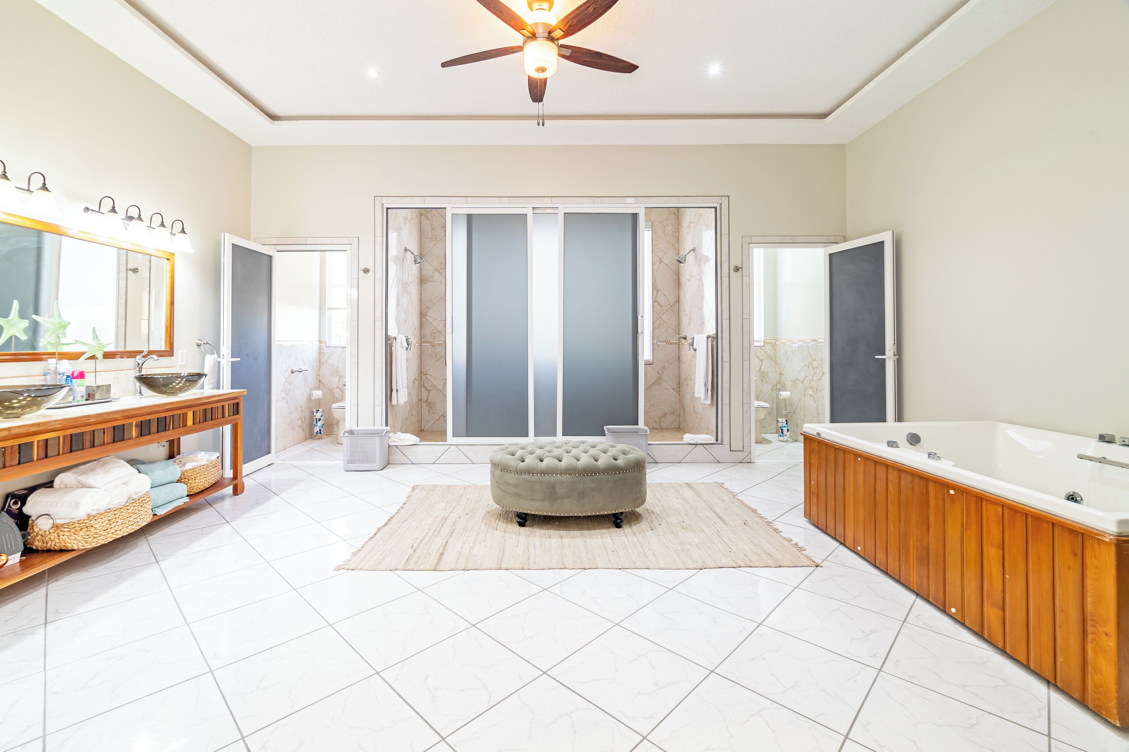 A spacious bathroom with a vanity, a large bathtub, and a ceiling fan.
