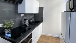 Una cocina moderna con encimeras negras, armarios blancos y un hervidor de acero inoxidable.